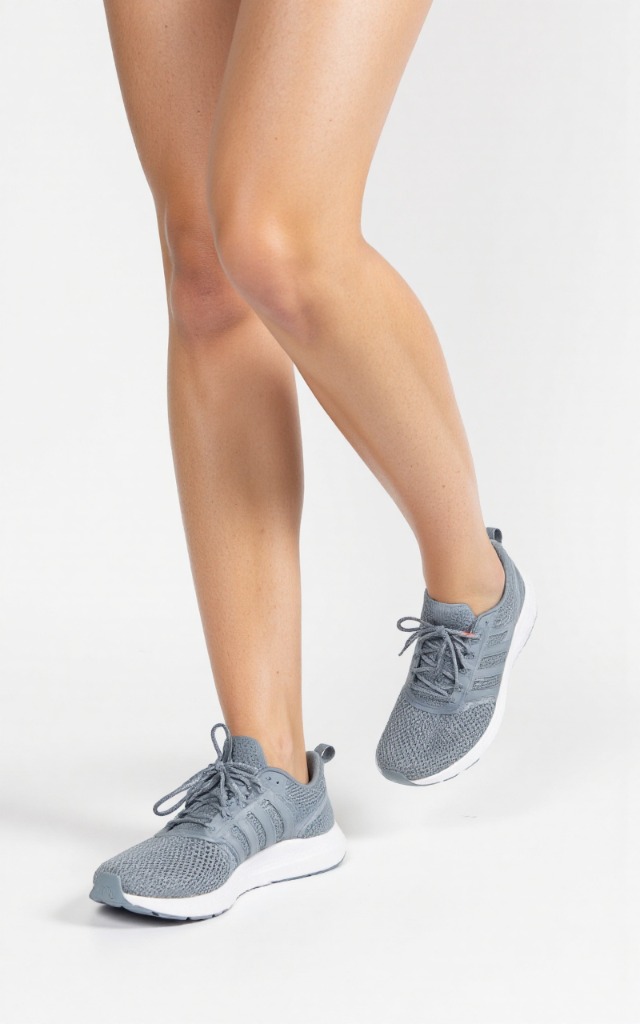 A female model wearing athletic shoes, against a white background, with a close   up of the feet